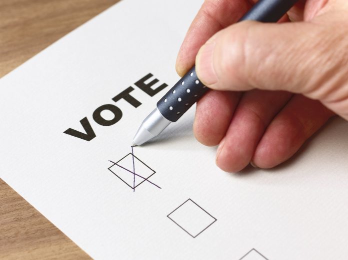 Senior man voting with cross